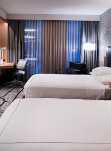 A modern hotel room with two beds, a wall-mounted TV, a desk with a chair, and contemporary decor ending the sentence.