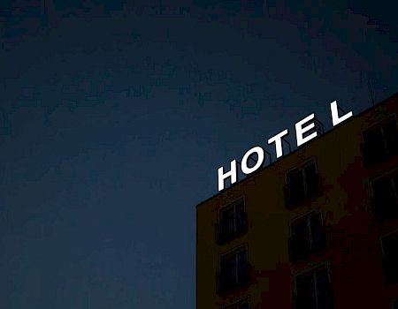 A building with the word "HOTEL" displayed at the top, with the letter "L" tilted, against a dark evening sky.