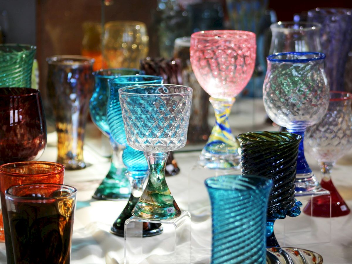 A collection of colorful, intricately designed glass goblets displayed on a flat surface in varying patterns and hues, including blue, red, and green.